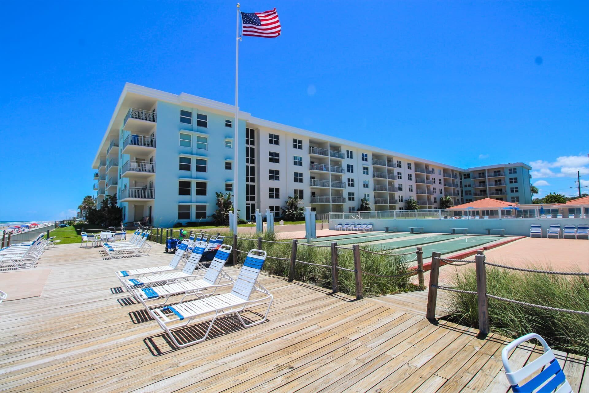 A hotel with multiple balconies, a pool area, and a beach deck with sun loungers.