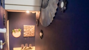 Una escalera conduce a un área de comedor con una mesa y sillas, un muro decorativo y una cesta en el suelo.