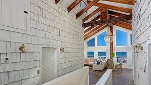 A spacious interior with a large bathtub, wooden beams, and a view of the ocean. - Sea Castle (New Smyrna Beach)