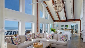 A spacious living room with a large sectional sofa, a dining area, and a view of the ocean. - Sea Castle (New Smyrna Beach)