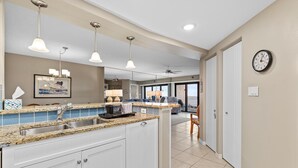 A kitchen with granite countertops, white cabinets, and pendant lighting. - Seascape Towers 524 (New Smyrna Beach)