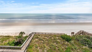 A beach view with a wooden boardwalk leading to a sandy area and a wooden staircase. - Seascape Towers 524 (New Smyrna Beach)