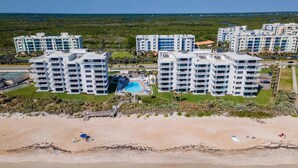 A beachfront hotel with multiple buildings, a swimming pool, and a beach area.