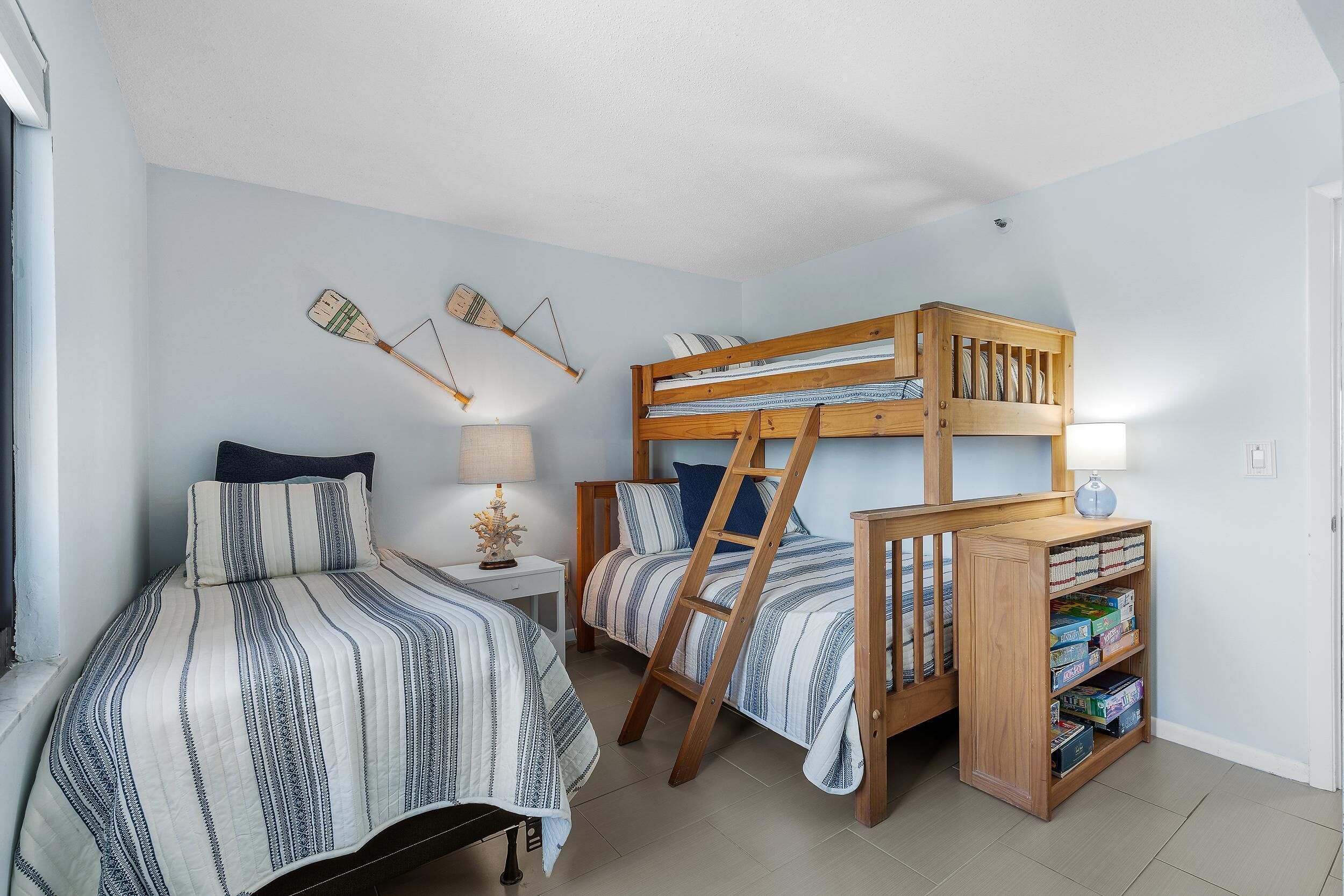 A bedroom with two beds, a wooden ladder, a nightstand, and a bookshelf.