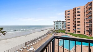 Un hôtel situé en bord de mer, doté d’une piscine, de chaises longues et offrant une vue sur l’océan.