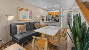 A compact living space with a sofa, a dining table, and a kitchen area in the background.