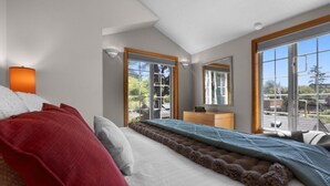 A bedroom with a large bed, a dresser, and a window with a view of the outdoors.