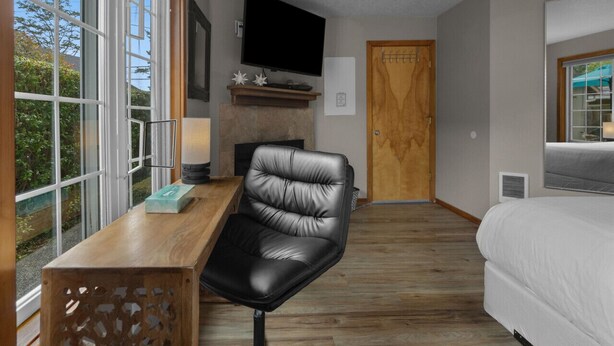 Une chambre à coucher avec un lit, un bureau avec une chaise, une télévision et une porte.