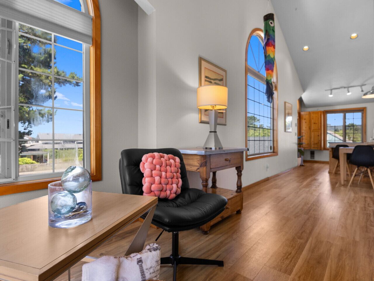 A spacious room with a wooden desk, a black chair, and a lamp.