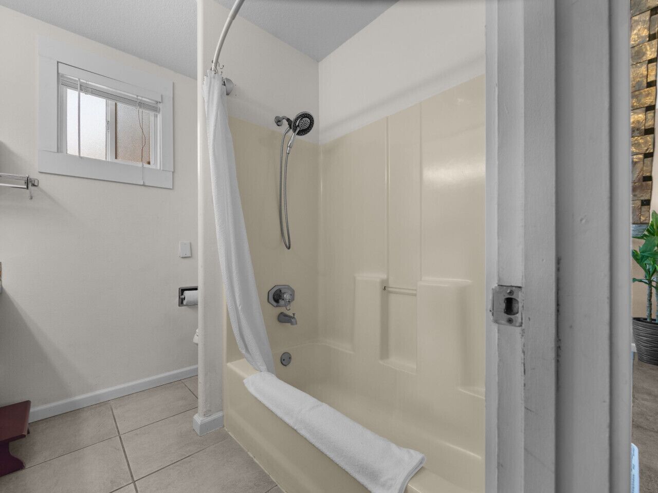 A bathroom with a bathtub, shower, and a window.