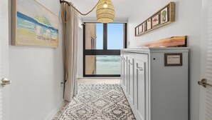 Um corredor com vista para o oceano, um quadro emoldurado, um armário de madeira e um tapete estampado.