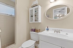 Une salle de bain comprenant des toilettes, un lavabo, un miroir et un meuble de rangement.
