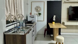 A compact kitchen with a wooden countertop, a sink, and a dining area with a table and stools. - Prado Guest House (Florianópolis)