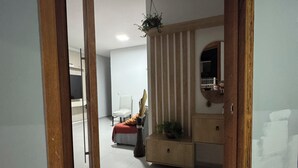 A room with a wooden door frame, a white chair, a small table, and a hanging plant. - Prado Guest House (Florianópolis)