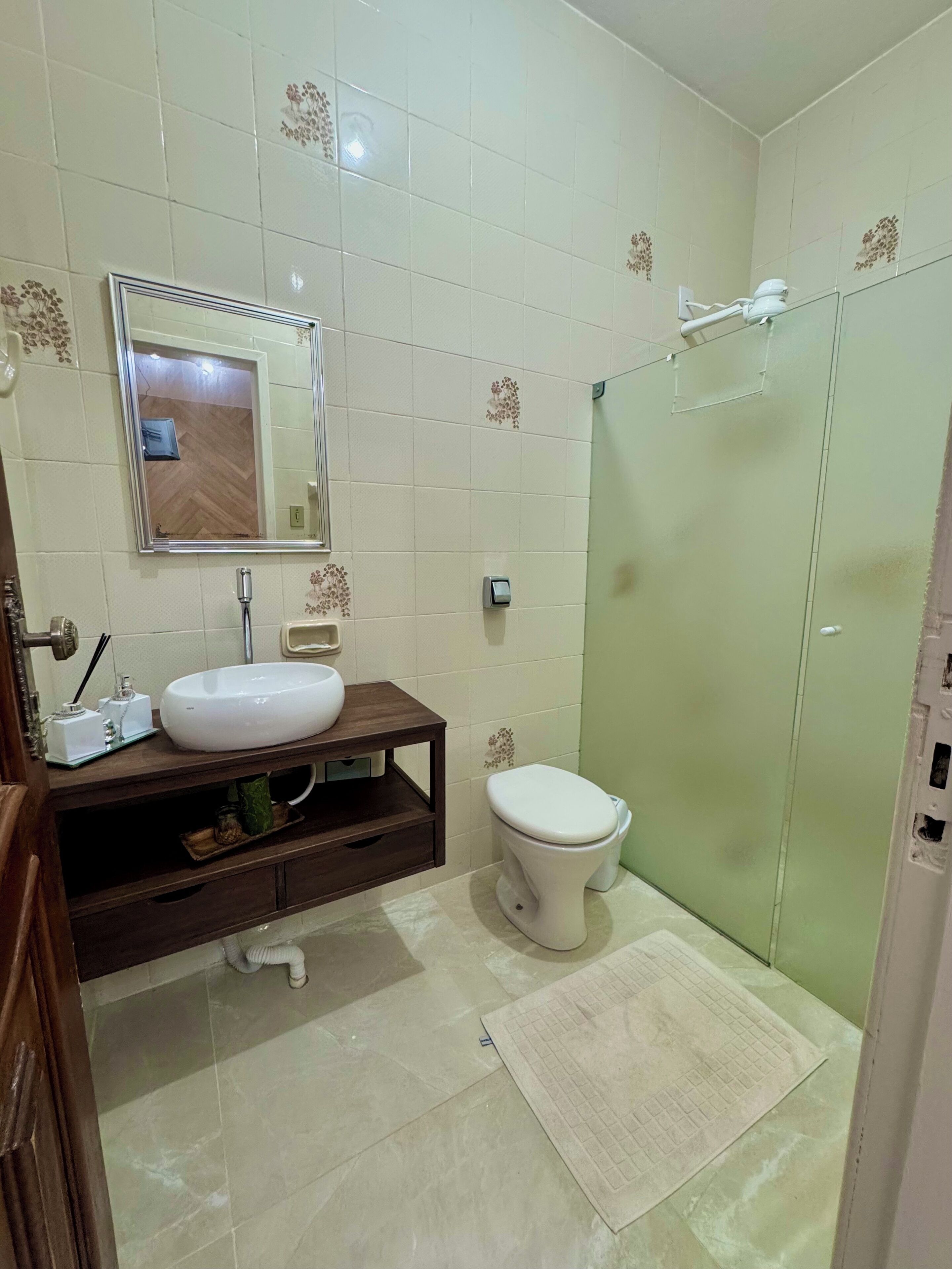 A bathroom with a white sink, a toilet, a mirror, and a shower area.
