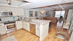 A modern kitchen with a central island, stainless steel appliances, and a dining area with a view.