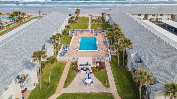 A resort with a swimming pool, beach view, and multiple guest rooms.