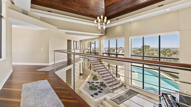 Un interior amplio con techo de madera, ventanas grandes y vista a una piscina.