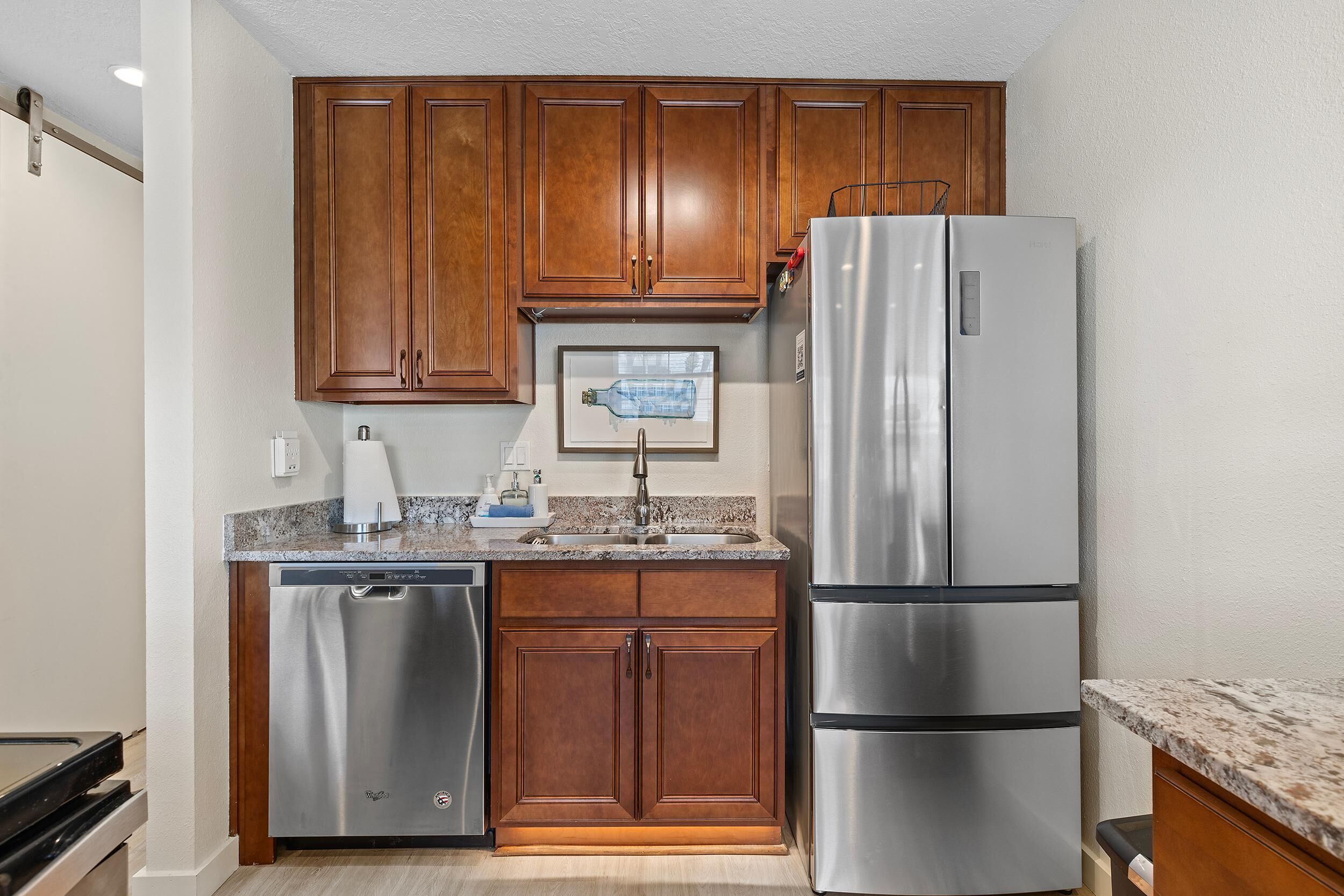 A compact kitchen with wooden cabinets, stainless steel appliances, and a granite countertop.