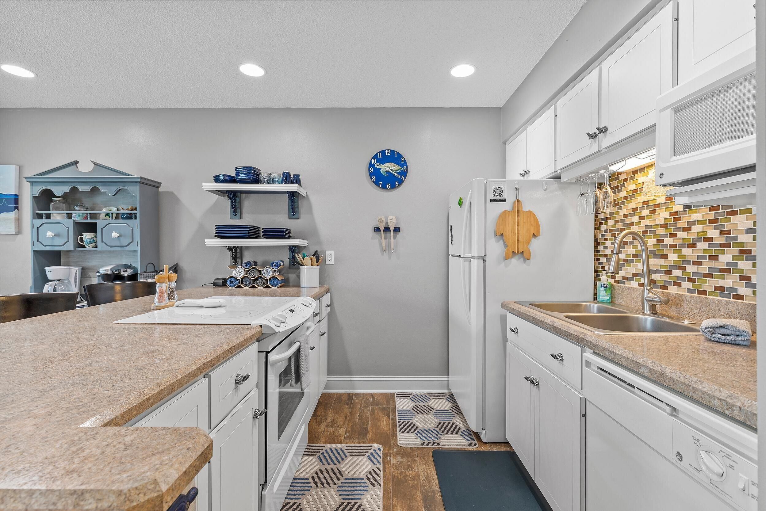 Una cocina moderna con armarios blancos, un reloj azul y un salpicadero con diseño.