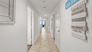 Un couloir avec un sol carrelé et un mur orné de panneaux indiquant les « RÈGLES DE LA PLAGE ».