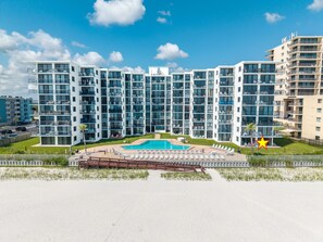 A modern multi-story hotel with a swimming pool and outdoor seating area.