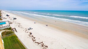 Ein Strand mit Poolbereich, einigen geparkten Autos und freiem Blick auf den Ozean.
