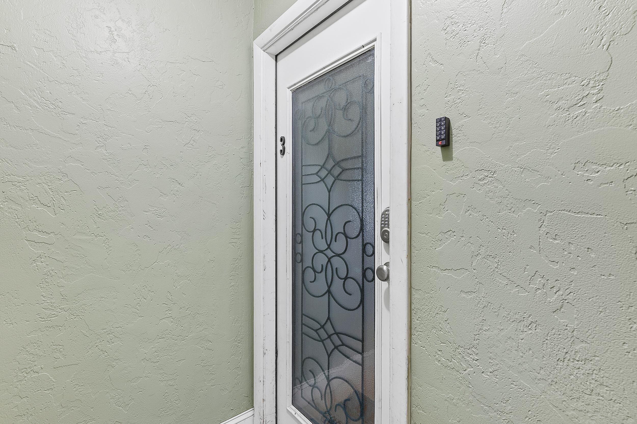 A door with a frosted glass panel and a keypad lock.