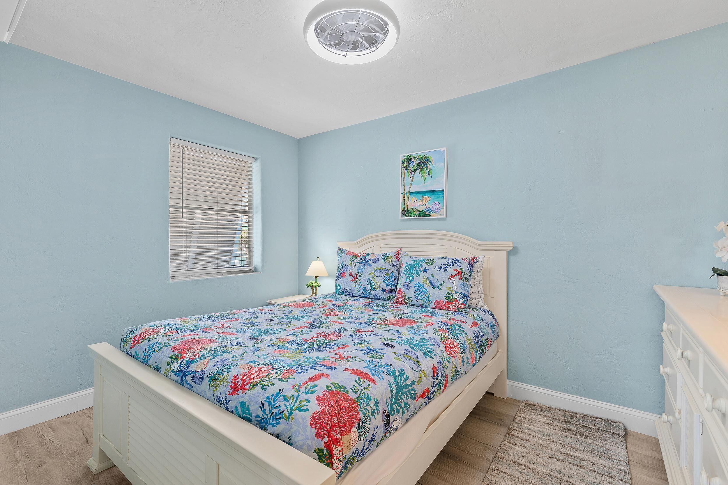 A bedroom with a bed, a nightstand, a lamp, and a painting on the wall.
