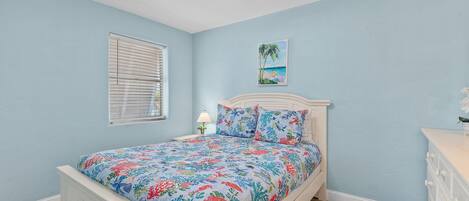 A bedroom with a bed, a nightstand, a lamp, and a painting on the wall.
