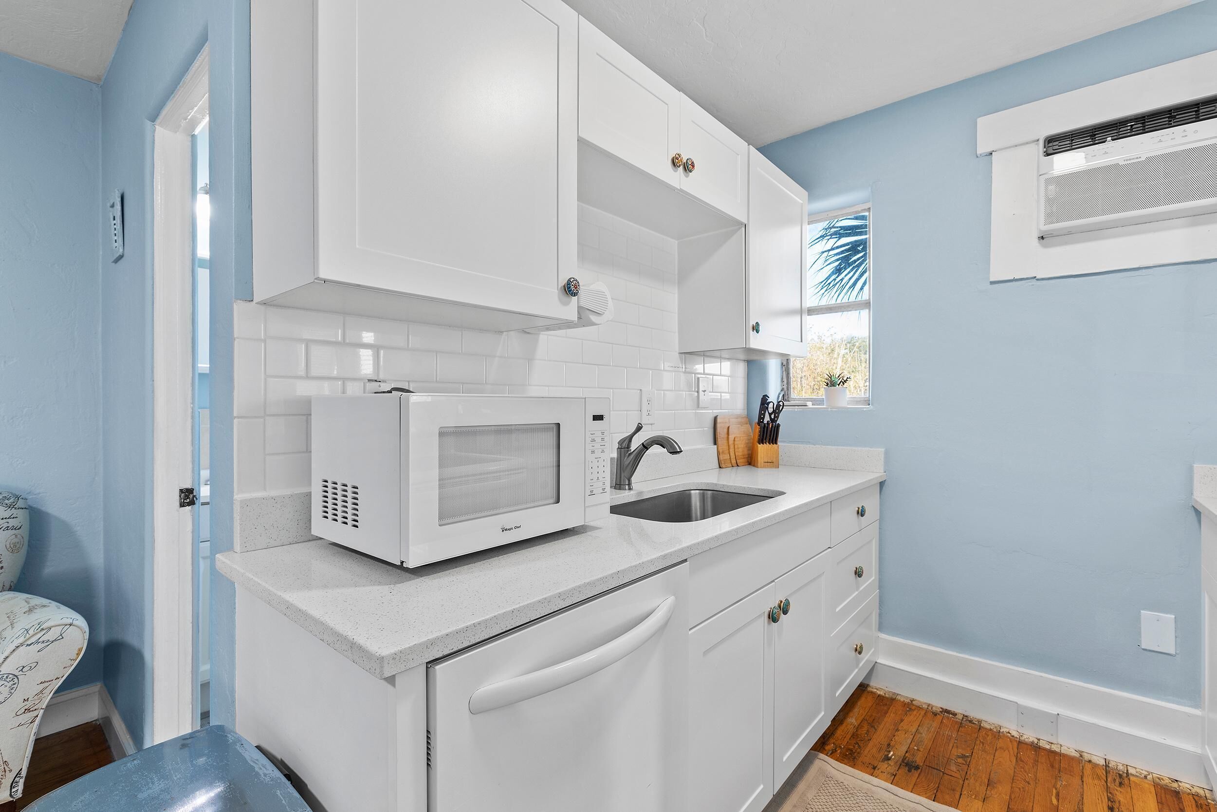 A kitchen with white cabinets, a microwave, and a sink.