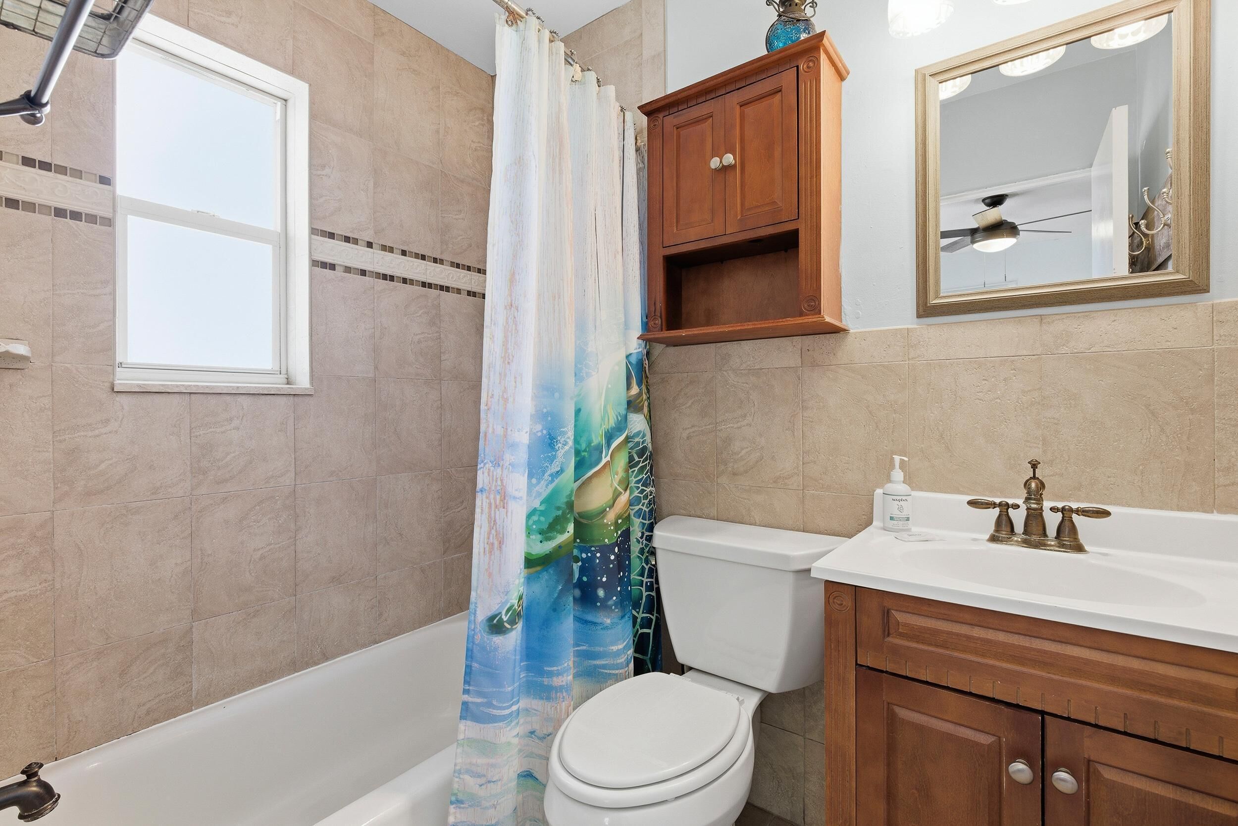 A bathroom with a bathtub, toilet, vanity, and a mirror.