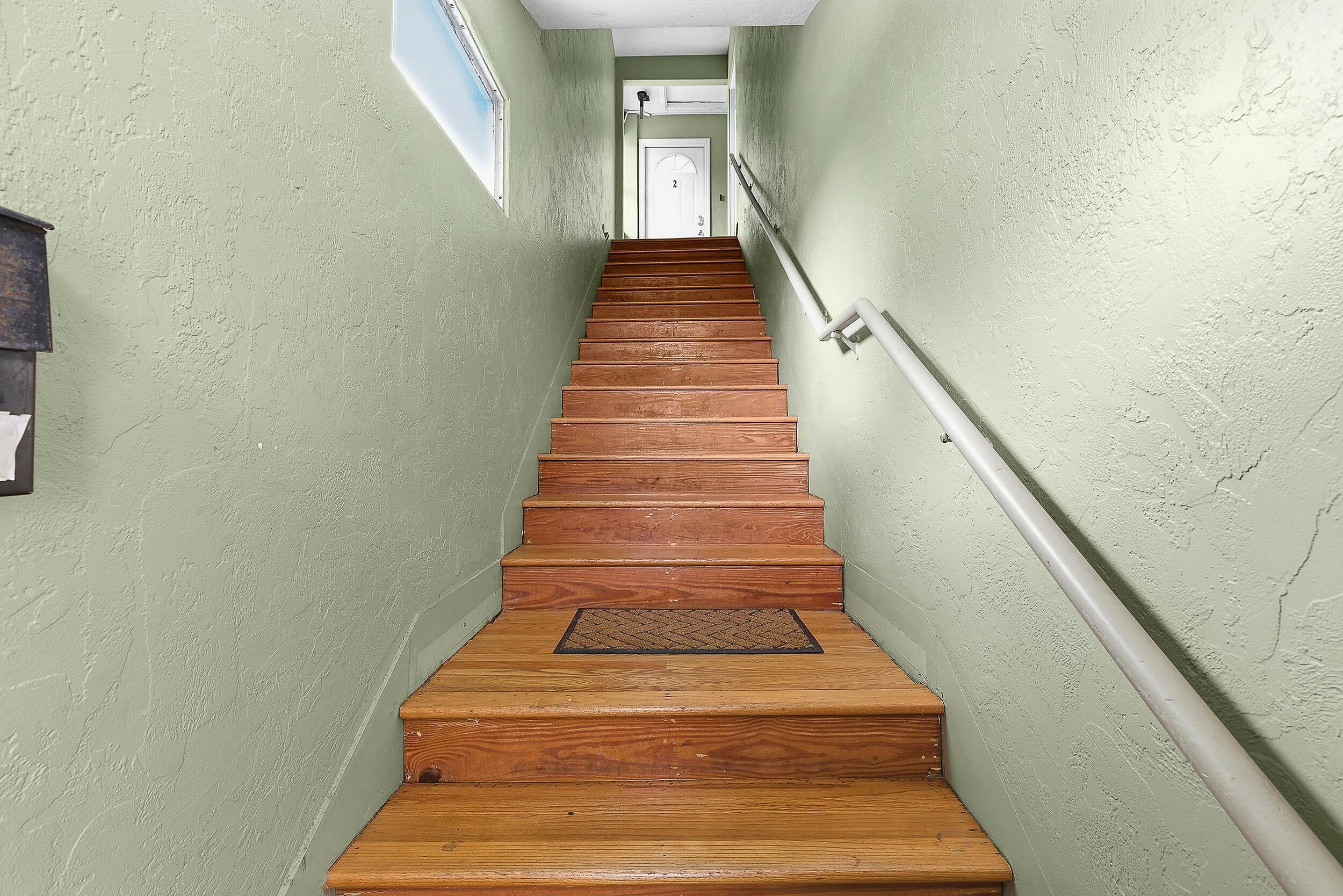Eine Holztreppe mit Handlauf, die zu einer Tür oben führt.