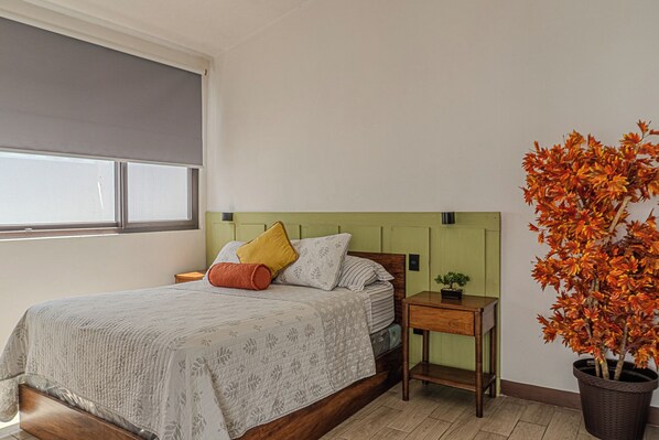 A bedroom with a bed, a nightstand, a potted plant, and a window. - Hermosa casa, con Parqueo propio, Ideal para pasar momentos en familia o pareja. (Jocotenango)