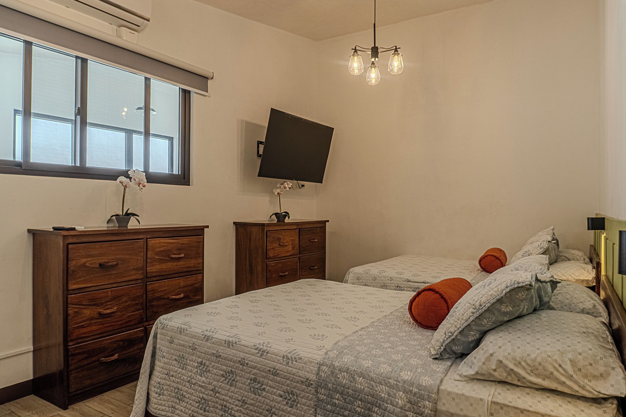 A bedroom with a bed, two nightstands, a TV, and a window.