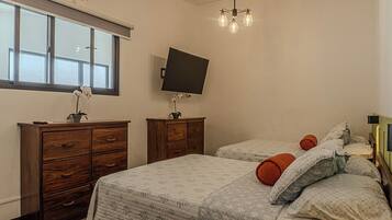 A bedroom with a bed, two nightstands, a TV, and a window.