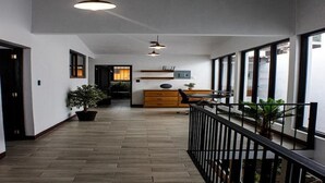 A modern hallway with wooden flooring, a black railing, and potted plants. - Hermosa casa, con Parqueo propio, Ideal para pasar momentos en familia o pareja. (Jocotenango)