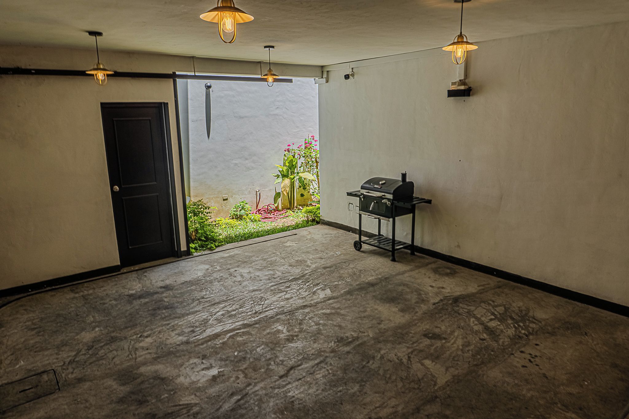 A spacious room with a concrete floor, a door, and a grill station.