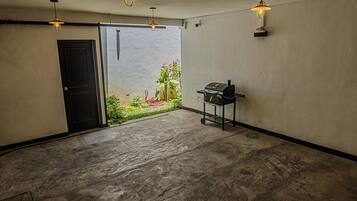 A spacious room with a concrete floor, a door, and a grill station.