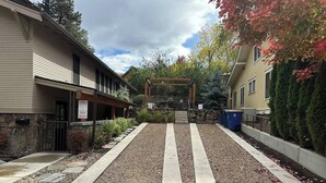 Une cour avec un chemin en pierre, une pergola et un mur en pierre.