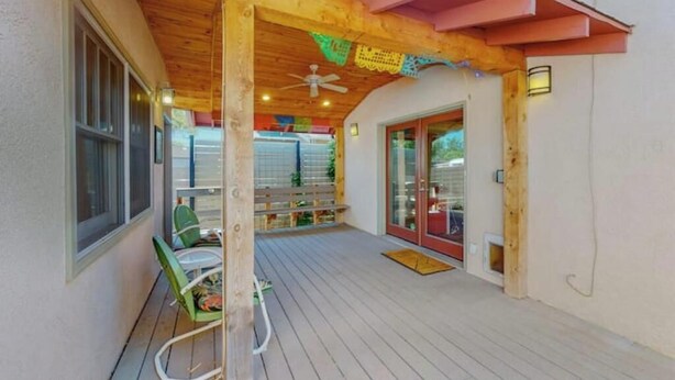 Un espace extérieur abrité, doté d’une terrasse en bois, d’un ventilateur de plafond et d’un banc.