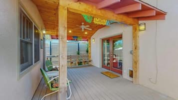Un espace extérieur abrité, doté d’une terrasse en bois, d’un ventilateur de plafond et d’un banc.