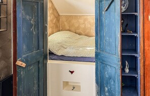 A bedroom with a bunk bed, a chest of drawers with a heart-shaped lock, and a shelf with decorative items.