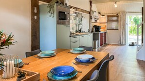 A modern kitchen with a wooden dining table set for four, featuring blue and white plates and a white candle holder.