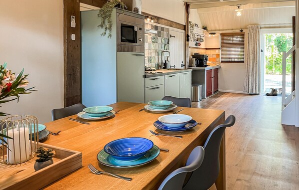 Cocina moderna con una mesa de comedor de madera para cuatro, con platos azules y blancos y un candelabro blanco.
