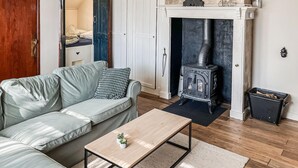 A cozy living room with a sofa, a coffee table, and a wood-burning stove.