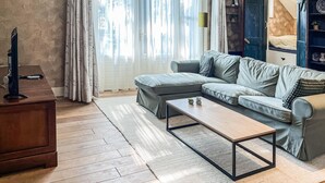 A modern living room with a grey sofa, a wooden coffee table, and a wooden desk with a computer.