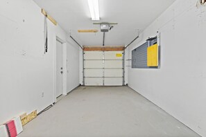 A hallway with a closed garage door, a ceiling-mounted projector, and a wall-mounted shelf. - Chic Townhouse in Northtown (Spokane)