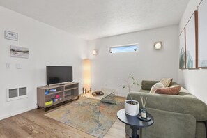 A modern living room with a flat-screen TV, a sofa, a coffee table, and a small side table with a candle. - Chic Townhouse in Northtown (Spokane)