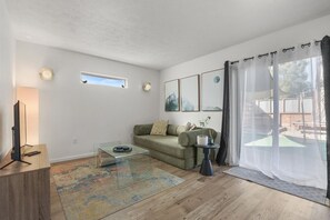 A modern living room with a sofa, a coffee table, a TV, and a window with curtains. - Chic Townhouse in Northtown (Spokane)